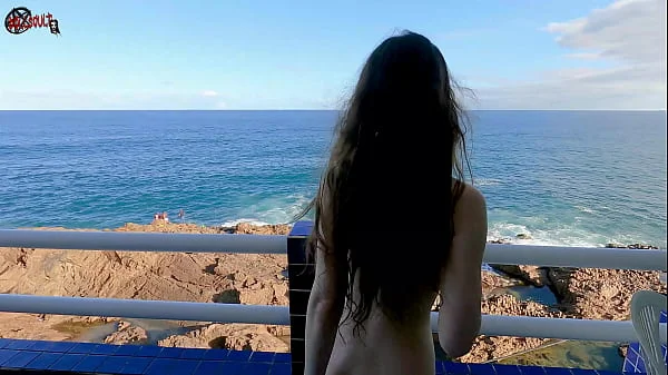 Mel strips on the balcony in front of people